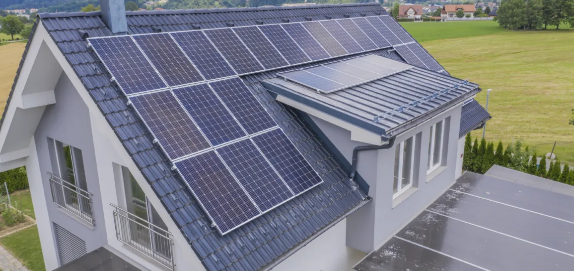 A high angle shot of a private house situated in a valley with solar panels on the roof